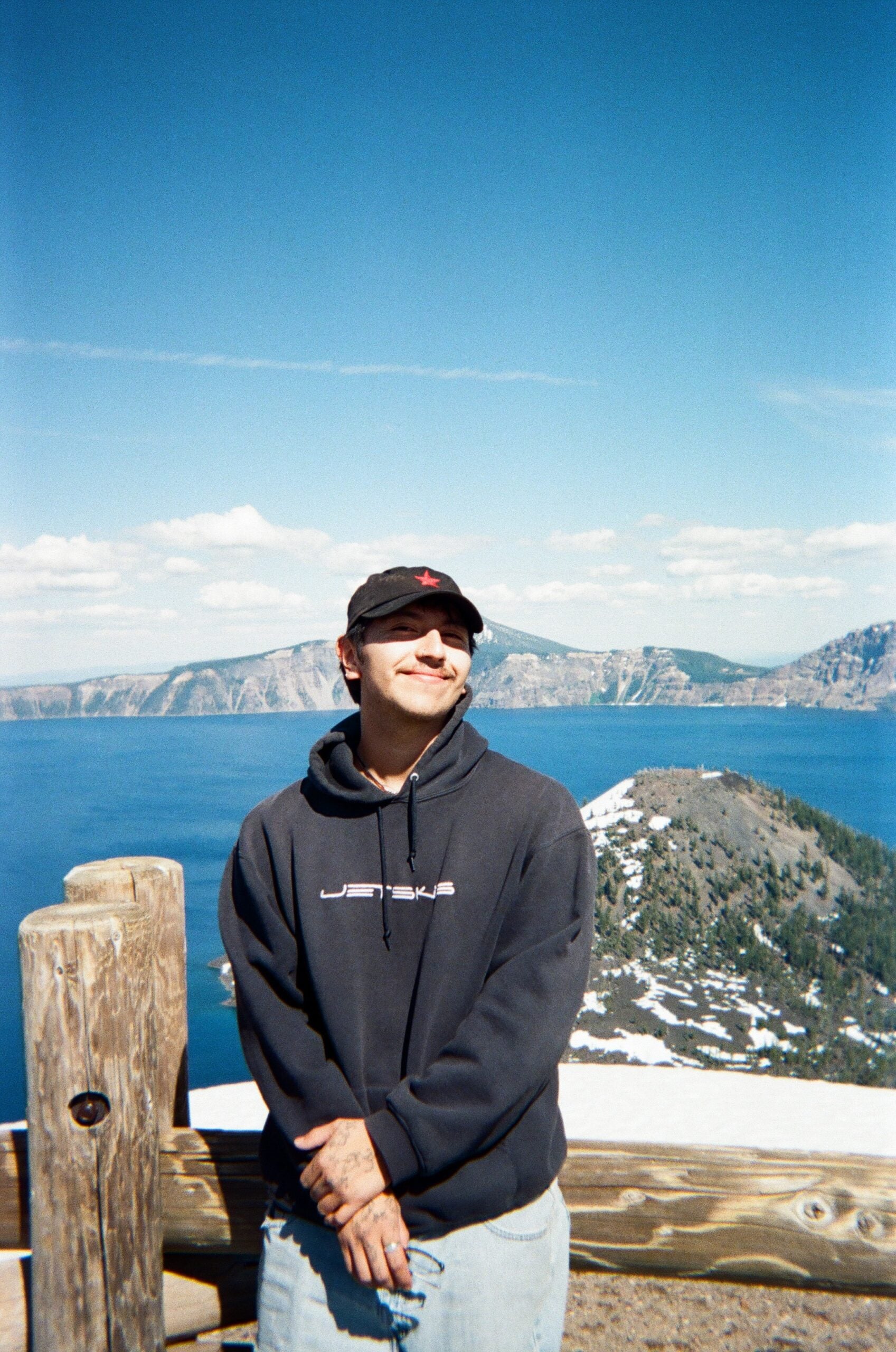 Man smiling in front of a vista with mountains and water