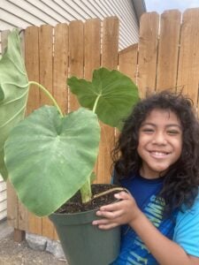 Child smiling and holding up a plant