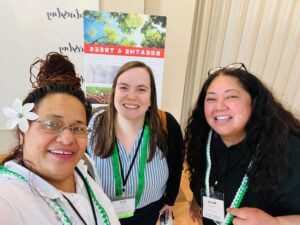 Three women smiling and wearing name badges at an event